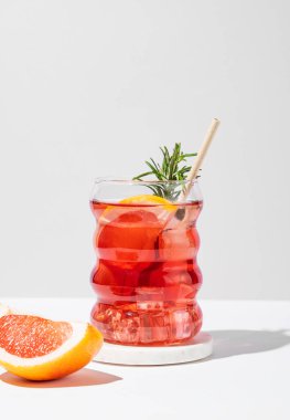 Hafif arka planda gölgeli bir bardakta greyfurt, biberiye ve buzla mocktail tazeleyici. Yaz turunçgil içeceği ya da kafe reklamları için limonata konsepti. Ön görünüm, boşluğu kopyala