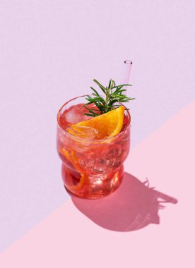 Kırmızı turuncu kokteyl ya da buzlu limonata ve pembe arka planda gölgeli biberiye. Kafe menüsü reklam afişi için yaz turunçusu içeceği konsepti. Boşluğu kopyala.