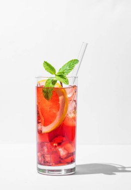 Greyfurtlu, naneli ve buzlu hafif arka planda gölgeli bir bardakta taze bir kokteyl. Yaz turunçgilleri ya da limonata konsepti. Ön görünüm ve boşluk kopyala.