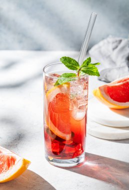 Hafif dokulu arka planda gölgesi ve narenciye meyvesi olan bir bardakta greyfurt, nane ve buz ile ferahlatıcı bir kokteyl. Yaz içeceği ya da limonata konsepti. Boşluğu kopyala.
