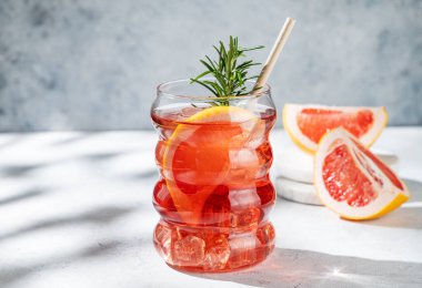 Limonata greyfurtlu, biberiyeli ve arka planda güneş ışığı olan bir bardakta buzlu. Yaz turunçgil içeceği ya da kafe menüsü reklam afişi için kokteyl konsepti. Ön görünüm, boşluğu kopyala.