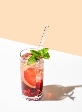 Greyfurt, nane ve buzlu beyaz sarı arka planda gölgeli bir bardakta taze bir kokteyl. Yaz turunçgilleri ya da limonata konsepti. Üst görünüm ve kopyalama alanı.