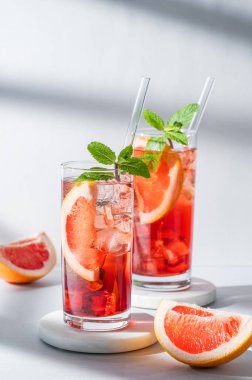 İki bardak kokteyl, greyfurtlu, naneli ve buzlu mermer üzerinde gölgeli açık arkaplan. Yaz turunçgilleri ya da limonata konsepti. Ön görünüm ve boşluk kopyala.