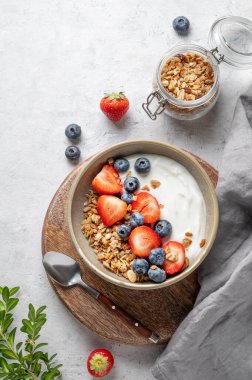 Tahta bir tahtanın üzerinde taze böğürtlenli doğal yoğurt, yaban mersini ve çilek. Sağlıklı, besleyici ve besleyici kahvaltı kavramı. Üst görünüm, alanı kopyala.
