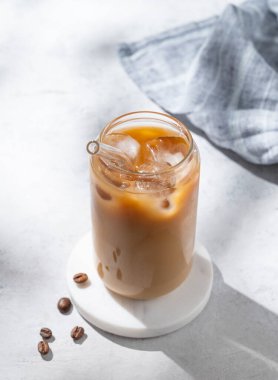 Sütlü buzlu latte kahve, kahve çekirdekleri ve sabah gölgeleri. Moda yazlık ferahlatıcı içecek konsepti. Üst görünüm, alanı kopyala.