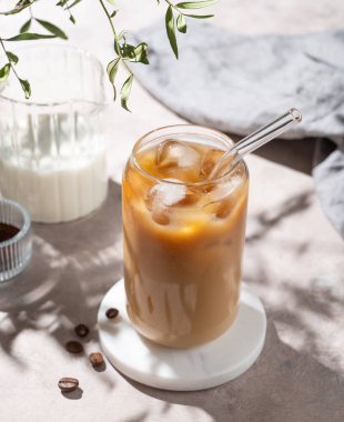 Sütlü buzlu latte kahve, kahve çekirdekleri ve sabah gölgeleri. Moda yazlık ferahlatıcı içecek konsepti. Üst görünüm.