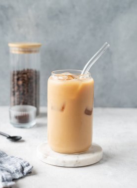 Kahve çekirdekleri ve kaşıkla hafif arkaplanlı mermer bir tahtada sütlü buzlu latte kahve. Moda yazlık ferahlatıcı içecek konsepti. Ön görünüm, boşluğu kopyala.