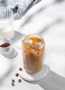 Sütlü buzlu latte kahve, kahve çekirdekleri ve sabah gölgeleri. Moda yazlık ferahlatıcı içecek konsepti. Üst görünüm, alanı kopyala.
