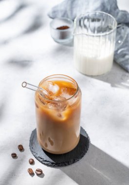 Sütlü buzlu latte kahve, kahve çekirdekleri ve sabah gölgeleri. Moda yazlık ferahlatıcı içecek konsepti. Üst görünüm, alanı kopyala.