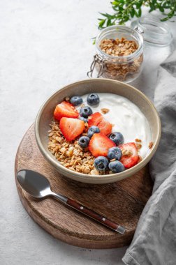 Tahta bir tahtanın üzerinde taze böğürtlenli doğal yoğurt, yaban mersini ve çilek. Sağlıklı, besleyici ve besleyici kahvaltı kavramı. Boşluğu kopyala.