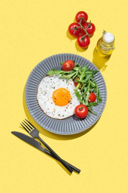 Koyu bir tabakta roka ve kiraz domatesli sahanda yumurta ve yağlı mangal. Reklam menüsü ya da afiş kafe için sağlıklı kahvaltı konsepti. Üst görünüm, alanı kopyala.