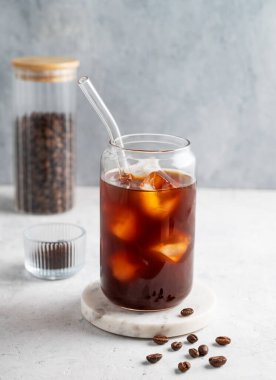 Kahve çekirdekli, hafif arka planda buzlu soğuk demlenmiş kahve bardağı. Moda yazlık ferahlatıcı içecek. Ön görünüm, boşluğu kopyala.