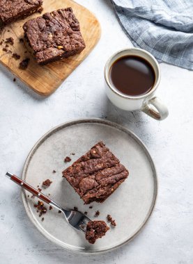 Hafif arka planda bir tabakta çikolatalı kek. Yanında da bir fincan taze kahve ve peçete. Ev yapımı tatlı pişirme konsepti. Üst görünüm, alanı kopyala.