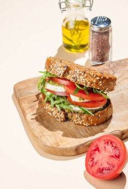 Domatesli tahıllı ekmek, mozzarella roka ve pesto taze sebzeler ve yağlı, ahşap bir tahta üzerinde. Reklam menüsü ya da afiş için kahvaltılık tost konsepti. Boşluğu kopyala
