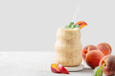 Şeftalili ve muzlu meyve püresi mermer tezgahın üzerinde tropikal meyveler ve güneş ışığıyla aydınlık bir zeminde. Reklam menüsü ya da afiş kafe için sağlıklı beslenme ve detoks diyeti kavramı. Ön görünüm, boşluğu kopyala.