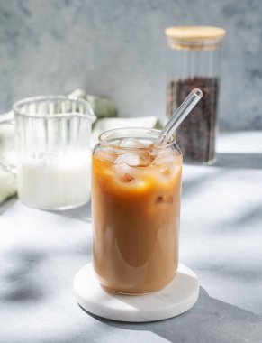 Kahve çekirdekleri ve sabah gölgeleriyle mermer tezgahta sütlü buzlu latte kahve. Moda yazlık ferahlatıcı içecek konsepti. 