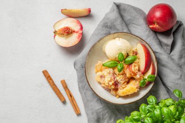 Şeftalili turta ya da vanilyalı dondurma kepçeli tarçeli turta. Arka planda hafif bir tabakta taze meyve ve otla birlikte. Yaz ev yapımı taze tatlı konsepti. Üst görünüm, alanı kopyala