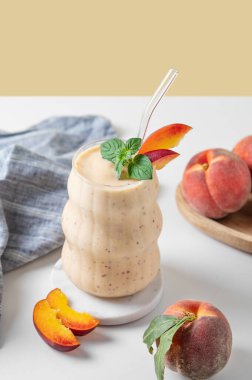 Şeftalili meyve suyu ve muzlu meyve suyu mermer tezgahın üzerinde tropikal meyve ve peçeteli sarı beyaz bir arka planda. Reklam menüsü ya da afiş kafe için sağlıklı beslenme ve detoks diyeti kavramı. Boşluğu kopyala.