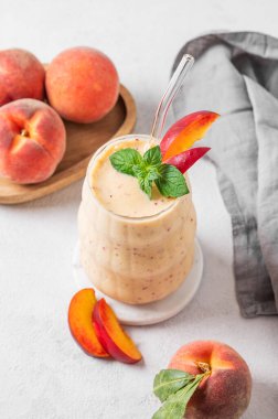 Şeftalili ve muzlu meyve suyu. Arka planda hafif bir bardakta, tropik meyve ve peçeteyle. Reklam menüsü ya da afiş kafe için sağlıklı beslenme ve detoks diyeti kavramı. Üst görünüm, alanı kopyala.