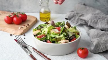 El yapımı parmesan peynirli vejetaryen salata, marul, domates, kızarmış ekmek, arka planda hafif bir kapta zeytin taze sebze, yağ ve çatal bıçakla birlikte. Sağlıklı beslenme konsepti. 