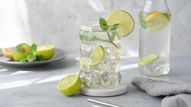 Taze kireç, nane ve buzlu mojito kokteyli. Arka planda hafif bir şişe ve hareketli bir gölge var. Turunçgil ile ferahlatıcı bir yaz içeceği kavramı. Ön görünüm.