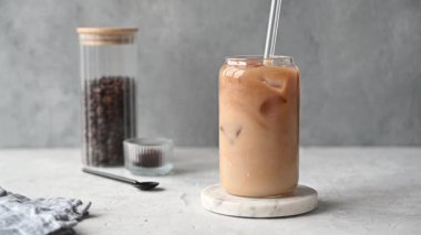 Süt ve buzlu kahve, kahve çekirdekleri ve sabah gölgeleriyle mermer bir tezgahta kamışla karıştırılır. Yaz ferahlatıcı içki konsepti.