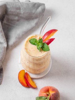 Şeftalili ve muzlu meyve suyu. Arka planda hafif bir bardakta, tropik meyve ve peçeteyle. Reklam menüsü ya da afiş kafe için sağlıklı beslenme ve detoks diyeti kavramı. Üst görünüm, alanı kopyala.