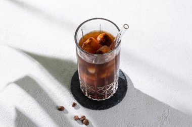 Kahve çekirdekleri ve sabah gölgesi olan hafif arka planda buzlu soğuk demlenmiş kahve toniği. Reklam menüsü kafe için yaz ferahlatıcı moda içecek konsepti. Üst görünüm, alanı kopyala.