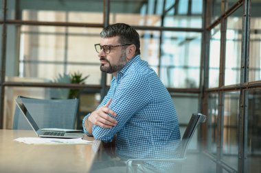 Side view of manager resting from work with laptop while sitting at the desk, using laptop