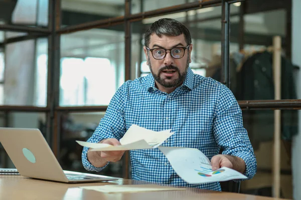 Shocked Caucasian Businessman Studying Annual Report While Working Office Using Fotos de stock