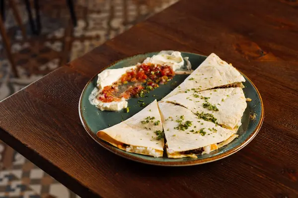 Lokantada servis edilen sos ve ekşi kremayla süslenmiş lezzetli tortilla.