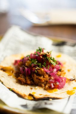 Lezzetli Cochinita Pibil Taco 'sunun üstünde soğan ve yeşil sebzeyle kaplanmış parlak bulanık arka planda servis edilen