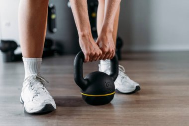 Kadın spor salonunda bir çaydanlık kapıyor, antrenmanına başlamak için hazırlanıyor.