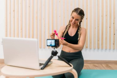 Fitness blogcusu Kegel egzersizleri hakkında bir video kaydederken gülümsüyor ve takipçilerine vajinal ağırlıkları gösteriyor