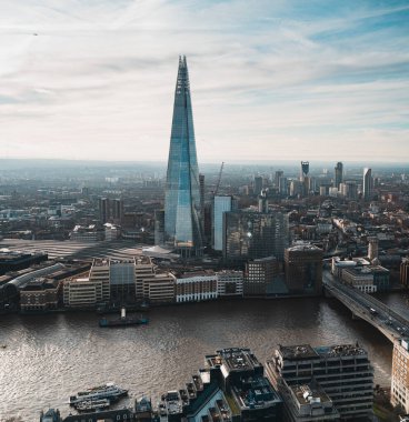 Londra şehri üzerinde hakimiyet kuran parçalı gökdelenin havadan görünüşü, alttan akan nehirler.