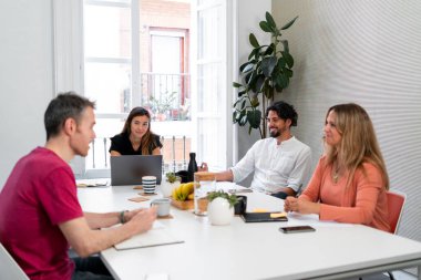 Modern bir ofiste verimli bir iş toplantısı sırasında dört iş arkadaşı bir projeyi tartışıyor.