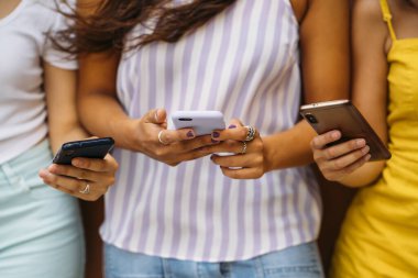 Bir grup arkadaş birlikte akıllı telefon kullanıyor, içeriği paylaşıyor ve sosyal medyadan keyif alıyorlar