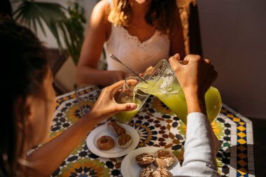 Öğrenciler geleneksel Fas hamur işleriyle dolu bir masaya taze meyve suyu dökerek değişim programı deneyimlerinin tadını çıkarıyorlar.