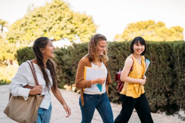 Üniversite değişim öğrencileri kampüste birlikte yürüyüp konuşuyor.