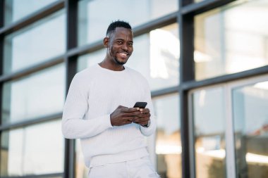 Modern ofis binasının yanında iş için cep telefonu uygulaması kullanan mutlu girişimci