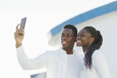 Gülümseyen turistler tatillerinin tadını çıkarırken akıllı telefonlarıyla selfie çekiyorlar.