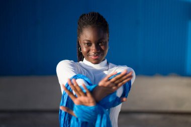 Çapraz kollar ve mavi eşarpla dur işareti yapan genç siyahi bir kadın açıkça reddedilme ya da sınırlama mesajı veriyor.