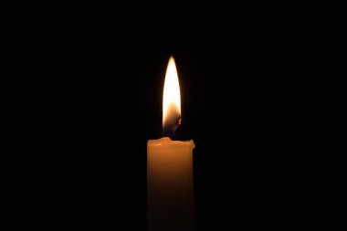 Close-up of a burning candle in the darkness with free copy space