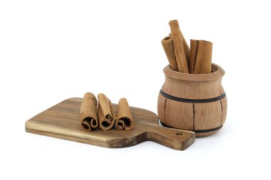 Tarçın beyaz arka planda izole edilmiş küçük bir ahşap tencereye yapışır.