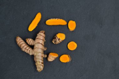 Koyu arkaplanda taze zerdeçal (curcumin) kökü, kopyalama alanı ile üst görünüm