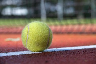 Sert saha yüzeyinde beyaz çizgi ve top alçak açılı görünümde tenis sahnesi