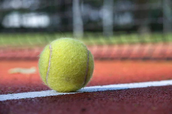 Sert saha yüzeyinde beyaz çizgi ve top alçak açılı görünümde tenis sahnesi