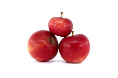 Farklı boyutlarda taze toplanmış kırmızı elmalar beyaz arka planda izole edilmiş.