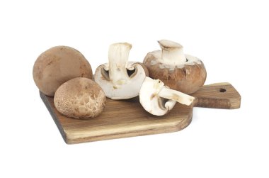 Beyaz arka planda izole edilmiş ahşap kesme tahtasındaki taze bebek Bella veya Cremini mantarları