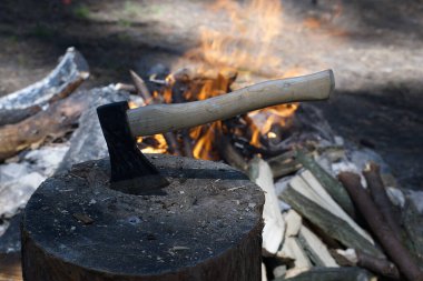 Ormanda kamp ateşi. Helikopter ön planda bir odun kütüğüne saplanmış. Sağlıklı, aktif bir yaşam tarzı konsepti.